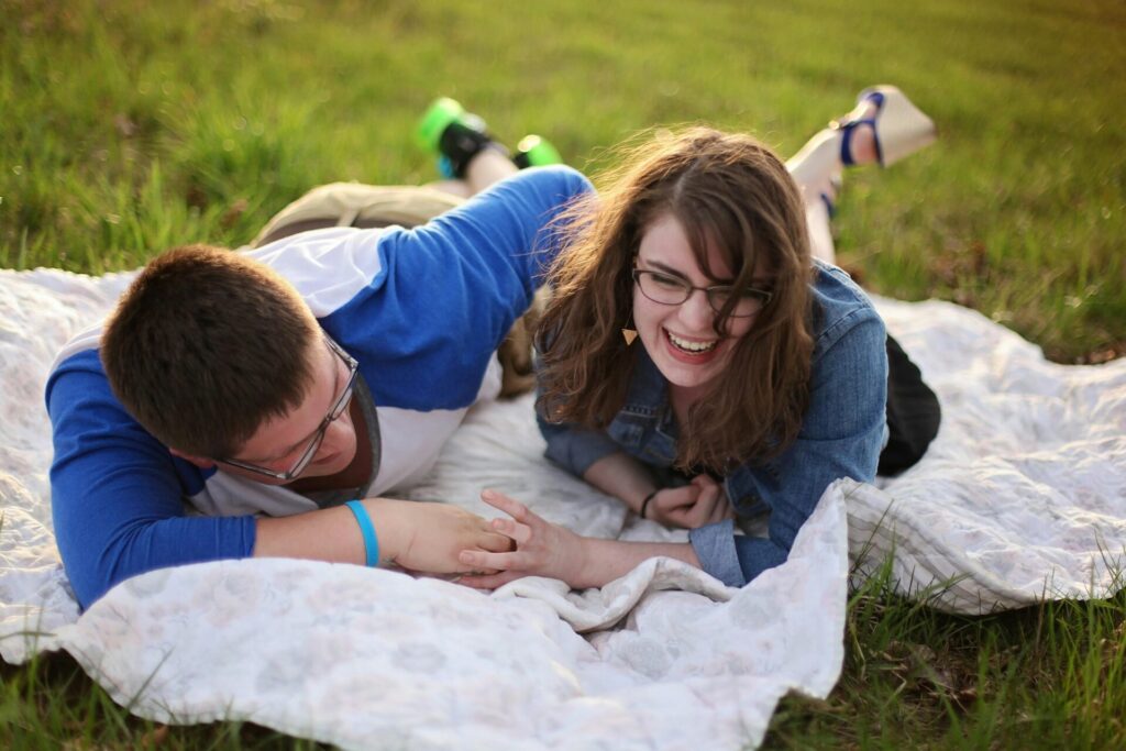Couple laughing and playfully teasing each other on a picnic blanket, illustrating the importance of joy, fun, and communication as key foundations for healthy relationships