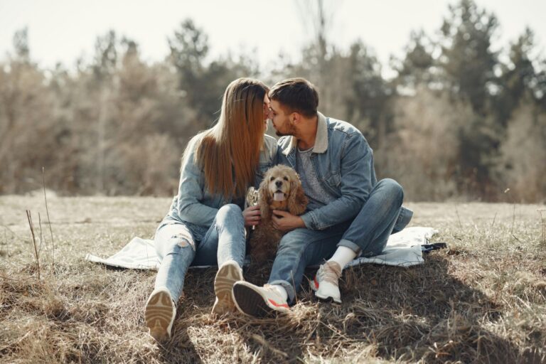 Couple sharing a kiss on a picnic blanket with their dog nearby, representing the foundations for healthy relationships built on love, trust, and mutual affection.