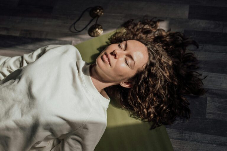 Woman lying on a yoga mat practicing breathing exercises for stress relief and relaxation.