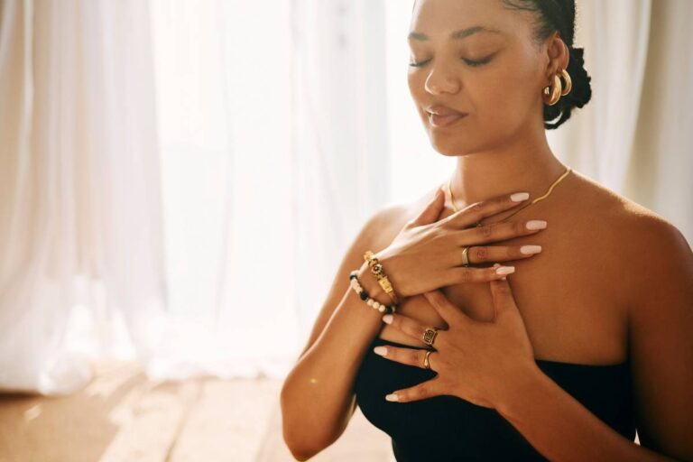 woman at home with hands on her chest, practicing breathing exercises for stress relief