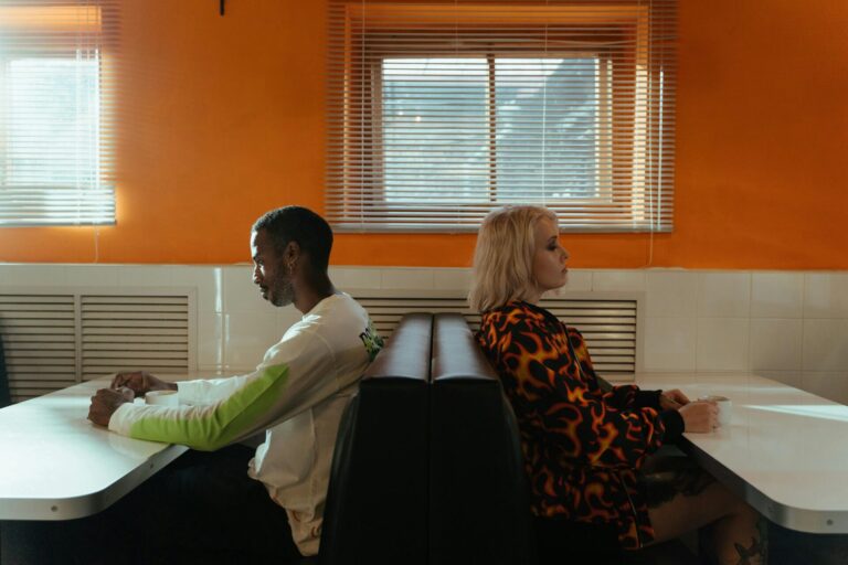 Couple sitting on separate benches, back to back, representing emotional distance and the realization that it's time to leave a toxic partner for personal well-being.