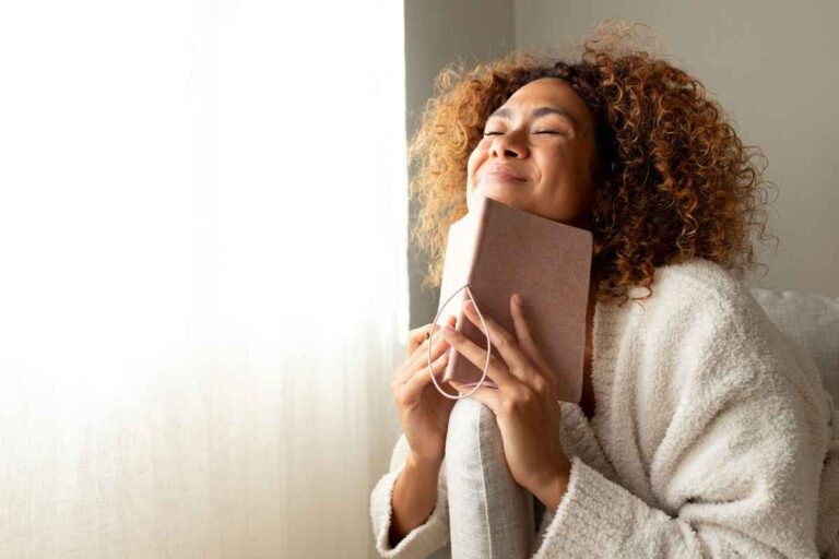 smiling woman leaning on a couch, reflecting and learning how to use the law of attraction in daily life