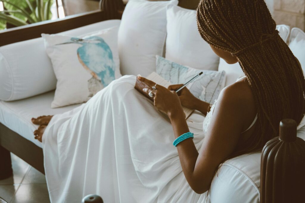 Woman sitting on a couch while journaling, showing the peaceful routine and proven benefits of daily journaling for mental well-being
