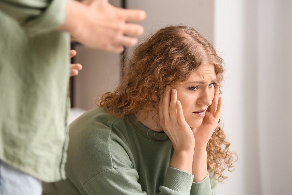 Scared woman listening to a man speaking, showing signs of discomfort in a tense relationship