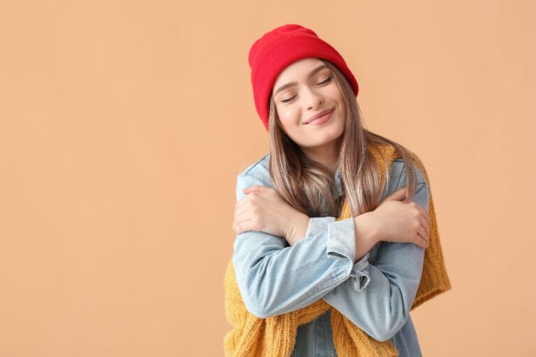 woman hugging herself and smiling, feeling confident and learning how to reframe negative self-talk