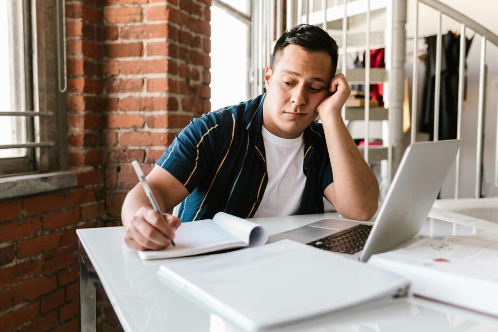 Boy reluctantly writing in a notebook, symbolizing resistance to tasks and the importance of finding ways to beat procrastination