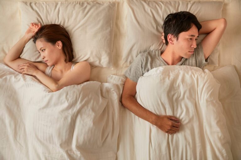 Couple lying in bed back to back, showing emotional distance and signs of a one-sided relationship