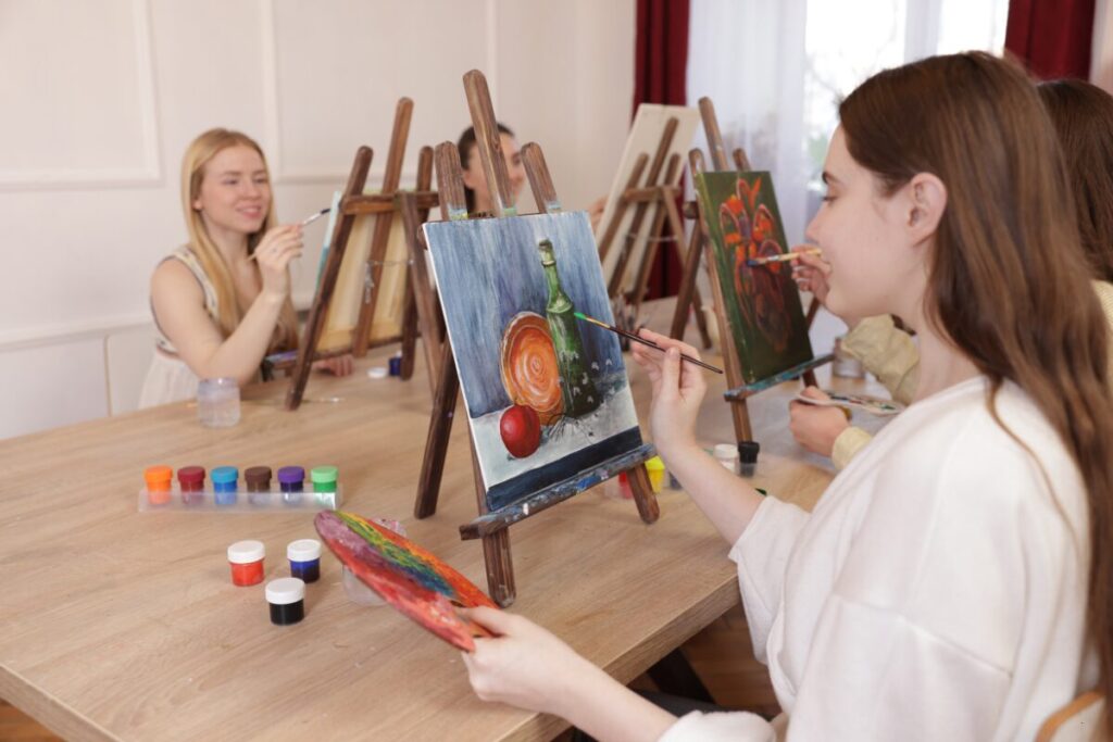 girls painting on canvases in a class, learning ways to get out of their comfort zone
