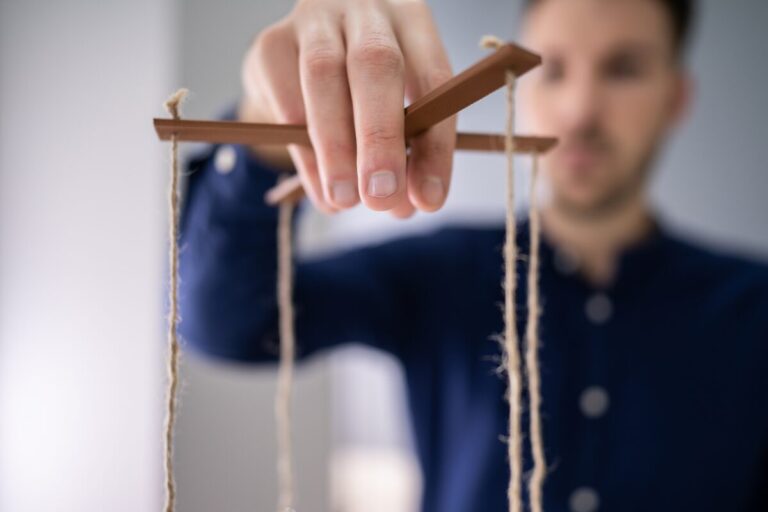 Man holding puppet strings symbolizing emotional manipulation tactics and psychological control