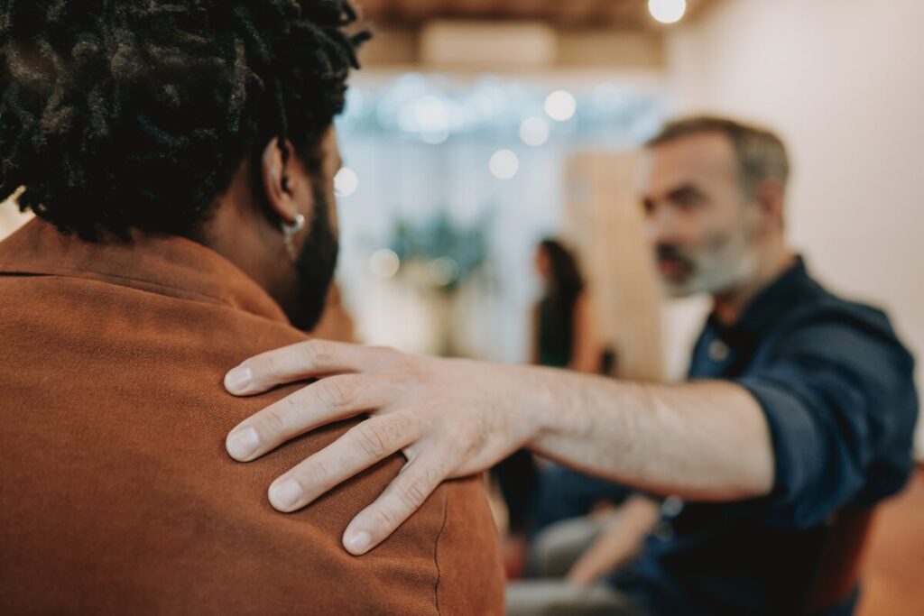 Man gripping another man's shoulder representing power imbalance and emotional manipulation tactics at work