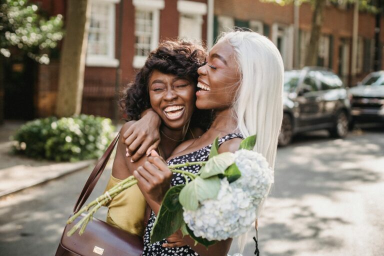 Two smiling friends hugging after reconciliation, showing how to forgive someone who hurt you.