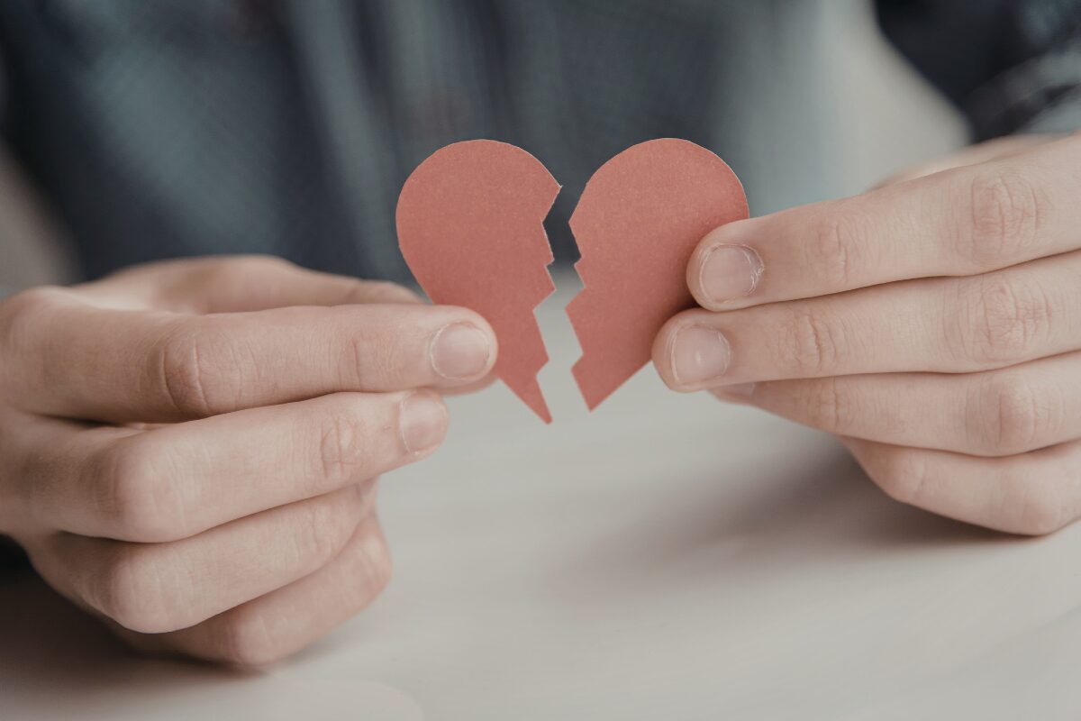 Man holding a torn heart symbolizing heartbreak and how to get over a breakup