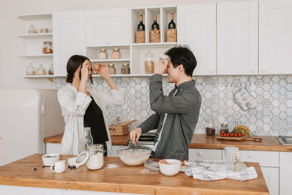 Couple cooking together in the kitchen, trying a creative budget friendly date idea.
