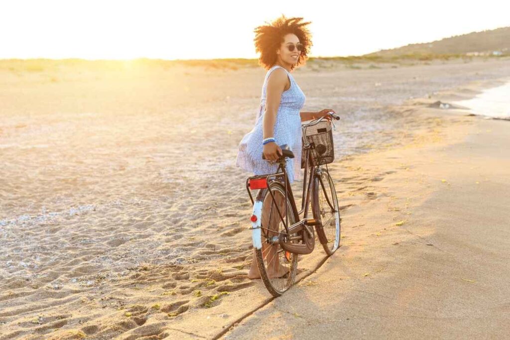 Solo date idea for women: woman happily riding her bicycle along the beach, feeling free and full of joy