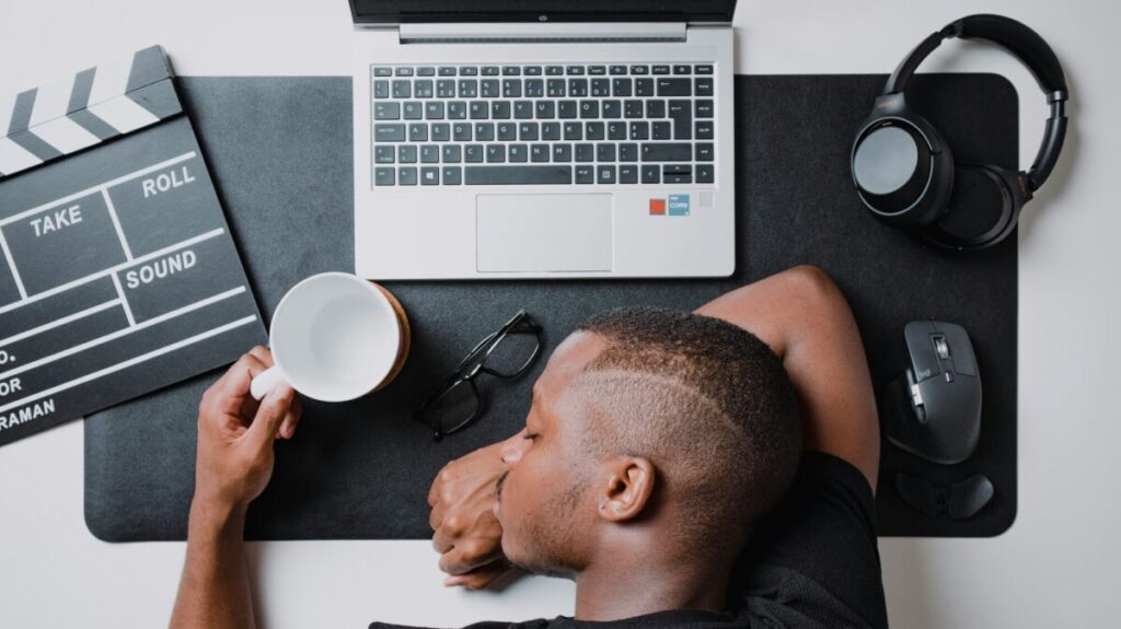 Very tired man resting his head on the desk while working on a computer, illustrating tips to recover from burnout.