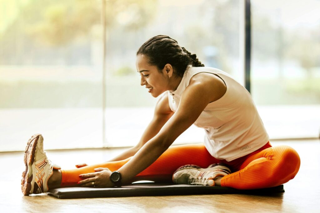 Woman stretching on the floor, preparing her mind and body to stay motivated to achieve her goals.
