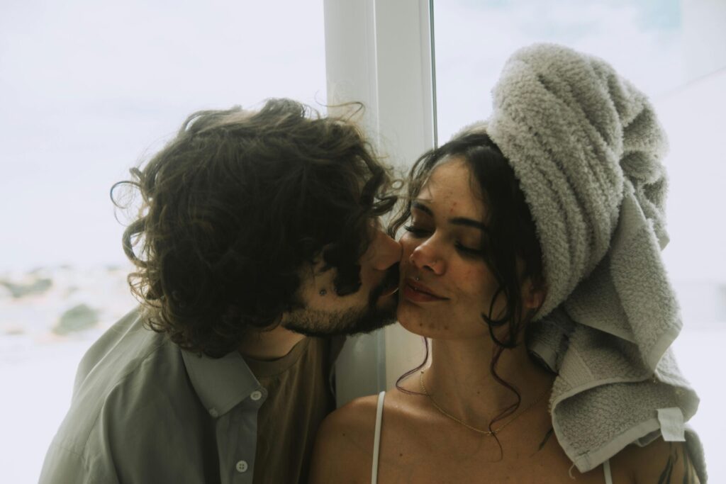 Man gently kissing his partner on the cheek, symbolizing healing and learning how to stop bringing up the past mistakes in a relationship.