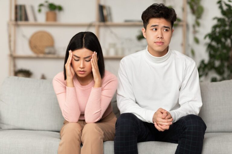 signs of an emotionally unavailable person couple sitting apart on couch feeling distant