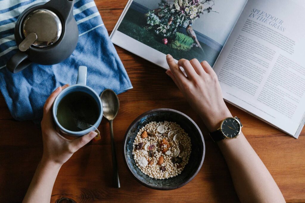 Healthy morning routine habit — table with a nutritious breakfast, hot tea, and book, representing mindful habits that support daily well-being.