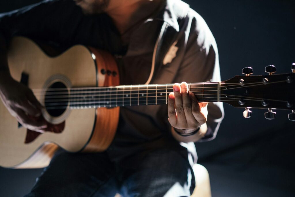 Habit tracking and personal growth — man practicing guitar at home, showing how building small daily habits leads to lasting skills.
