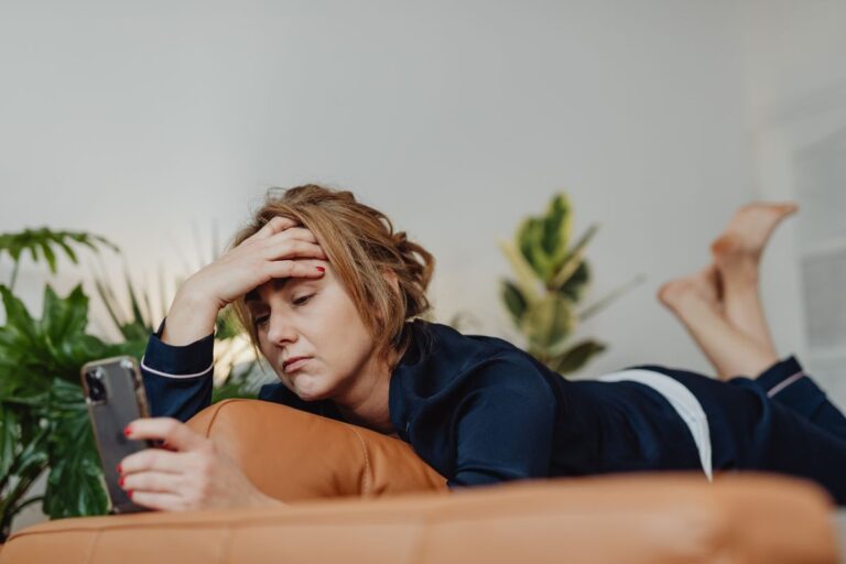 Natural ways to calm stress at home: woman lying on the sofa looking exhausted and stressed, seeking relaxation