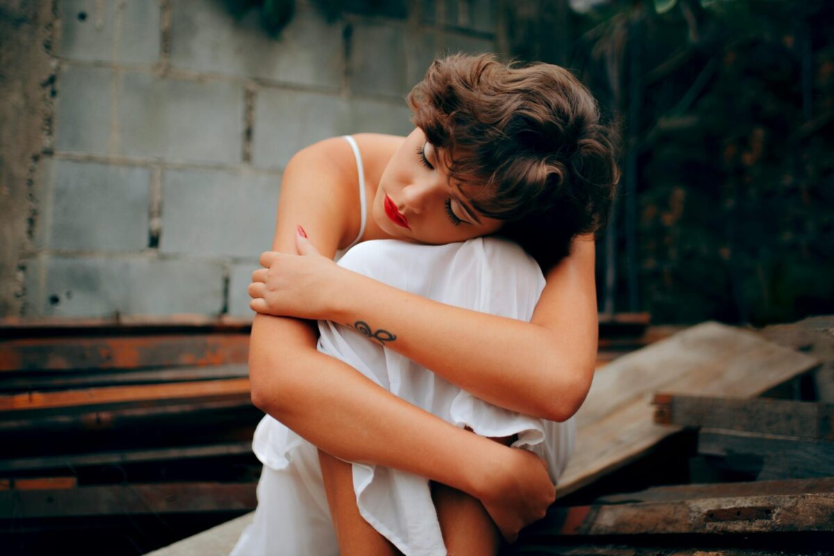 “Visual expression of emotion matching famous quotes about fear of failure – a woman sits hugging her knees, reflecting sadness and self-doubt.