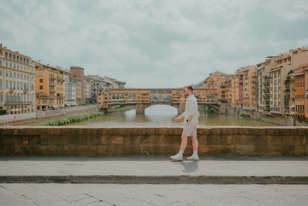 Young man walking across a charming old bridge above a river — symbolizing emotional freedom and things to stop caring about in life.
