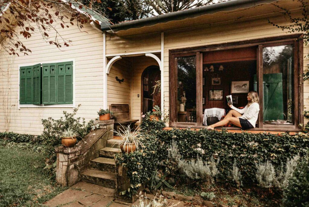 Woman sitting on the porch, deeply focused while reading inspiring books about money mindset.