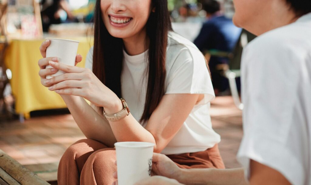 Two women chatting over coffee while gossiping — capturing everyday social behavior that may reflect signs of drama addiction.