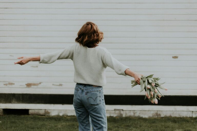 A woman spinning joyfully outdoors with a bouquet in hand — a beautiful moment that reflects subtle signs you truly love yourself.