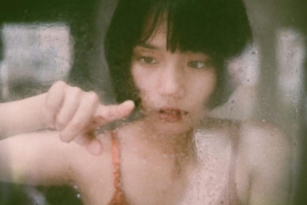 Woman drawing on a foggy mirror, facing her emotions with the help of journal prompts for sadness.