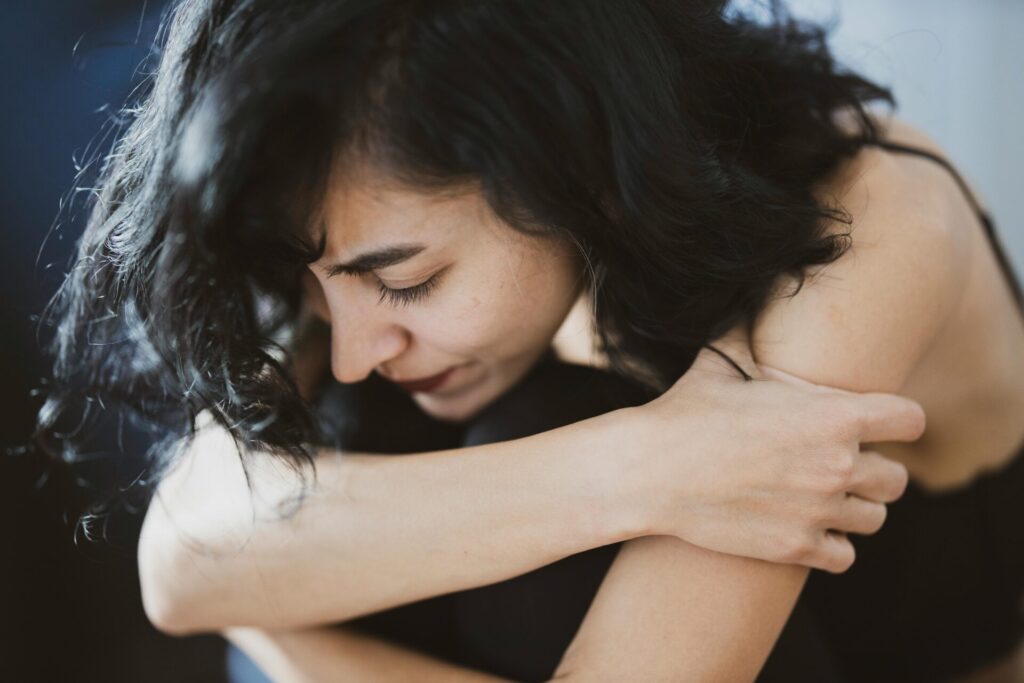 Sad woman sitting on the floor hugging her knees—symbolizing emotional pain and the need for techniques for effective emotion regulation.