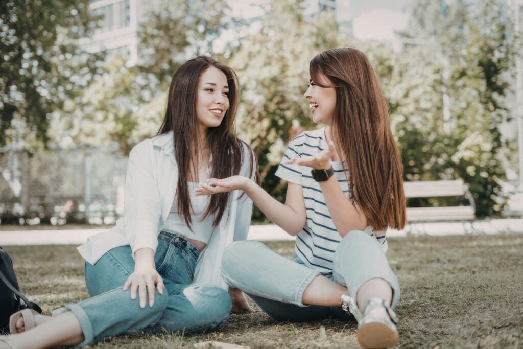 Two young women are talking while sitting on the ground in a park.
- why you can't change people