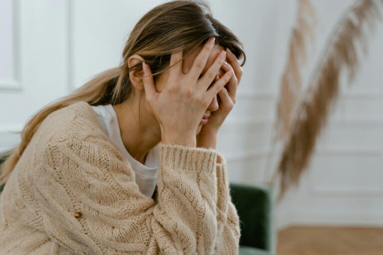 Woman covering her face with both hands, feeling overwhelmed by early signs of emotional abuse in a relationship, including fear and emotional distress.