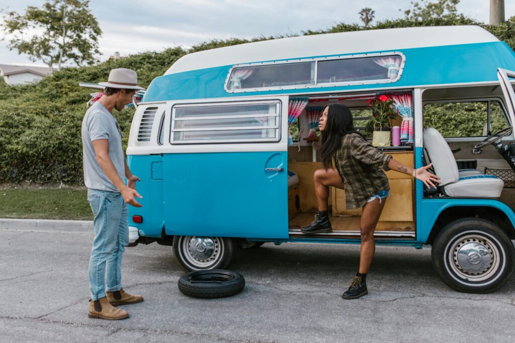 A couple arguing next to their car, with a car tire on the ground, highlighting a tense moment in their relationship. A typical scene showing the challenges of how to reconnect with your partner after a fight.