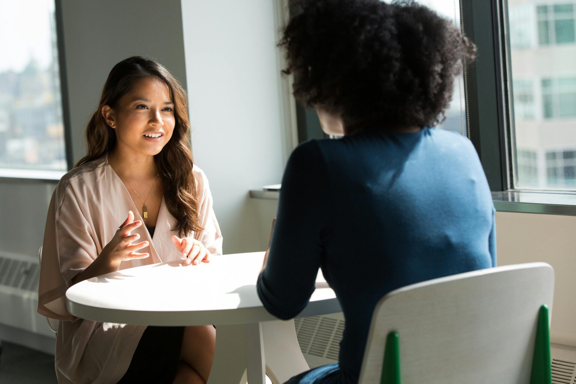 Two women talking at a table, discussing emotional topics and exploring reasons why some people never apologize.