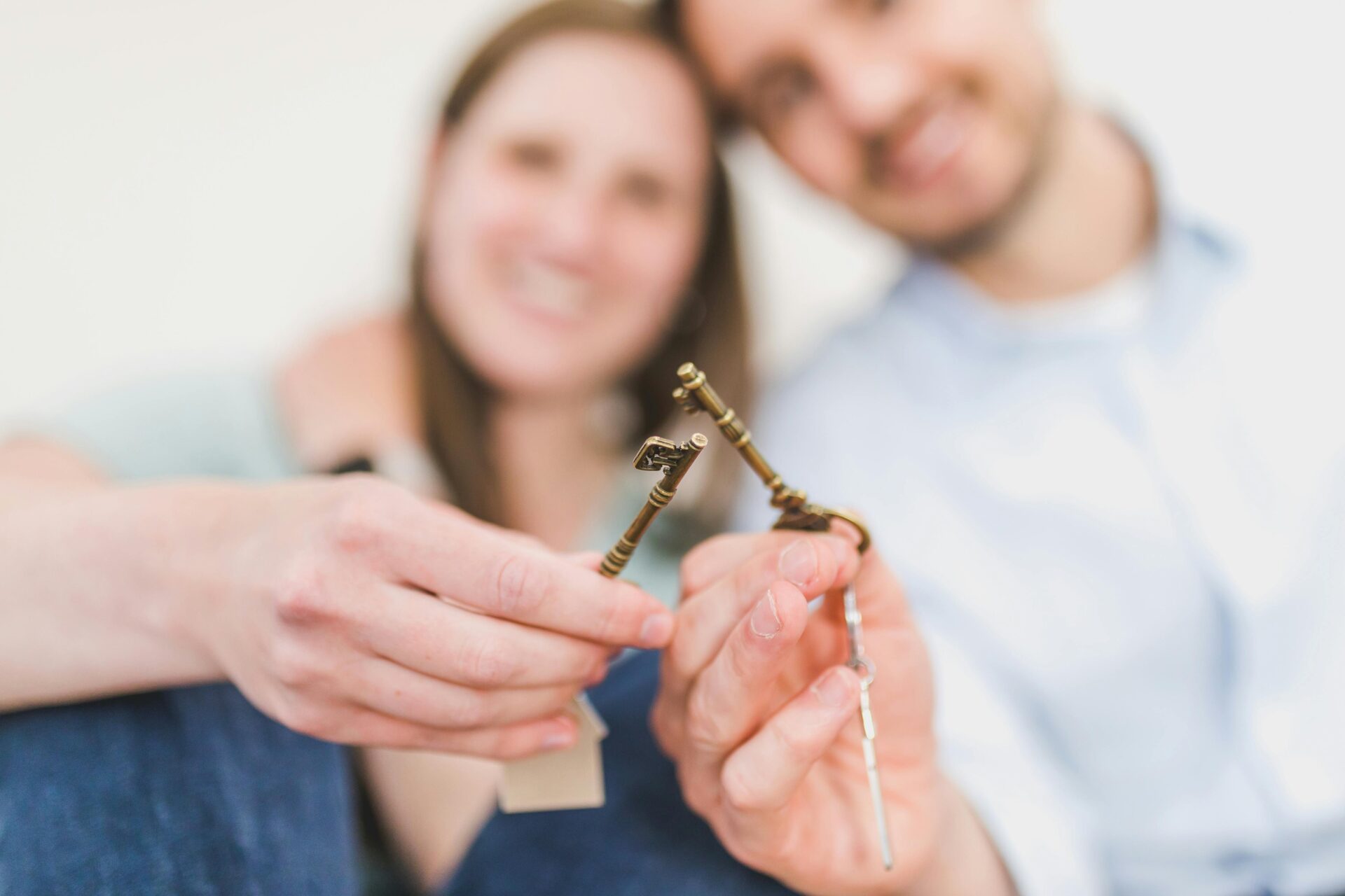 Happy couple holding a key in front of the camera, symbolizing a new chapter and the important things to discuss before moving in together.