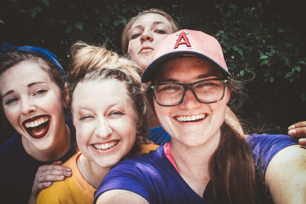 four friends taking a selfie and smiling, reflecting the bond and fun moments that are part of how to be a good friend.