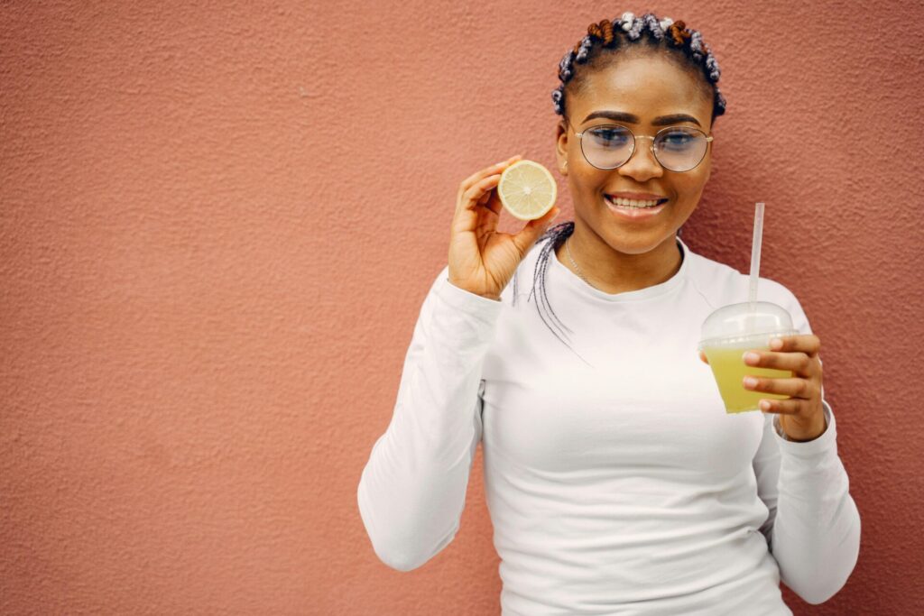 Happy woman holding a lemon and drinking a healthy juice, embracing lifestyle changes and discovering how to improve yourself after a breakup.