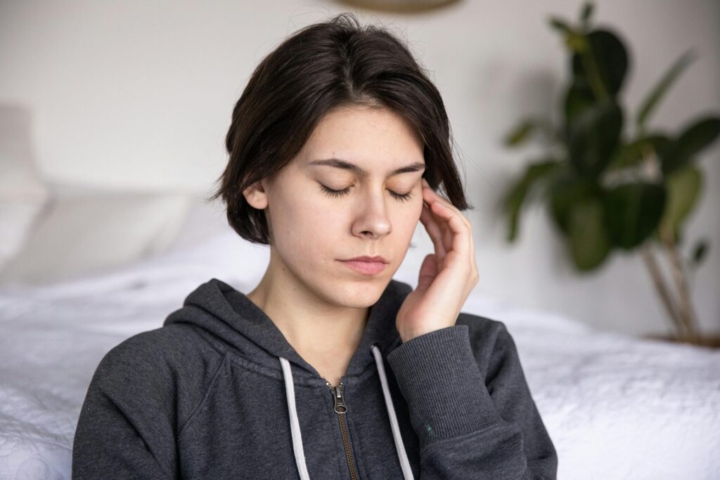 Middle-aged woman with closed eyes gently touching her head—practicing calmness and showing a moment of peace linked to how to stop overthinking after a first date.