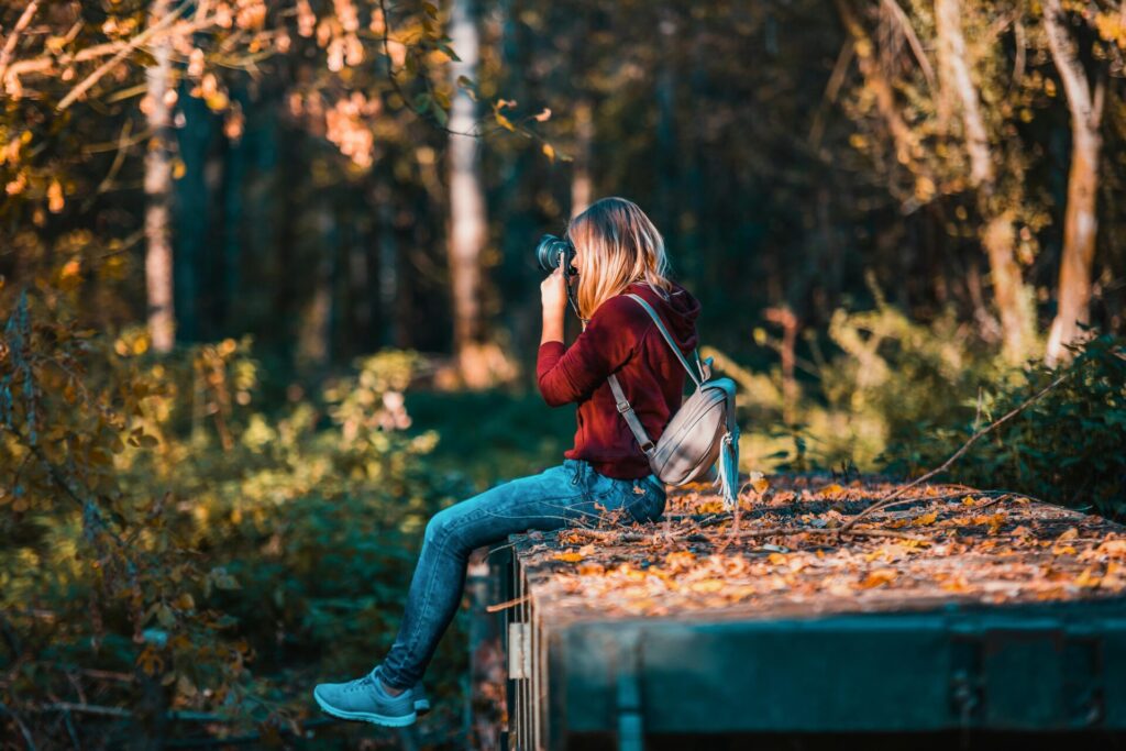 Woman in nature with a camera, capturing photos, representing distractions as reasons why you don't achieve goals.