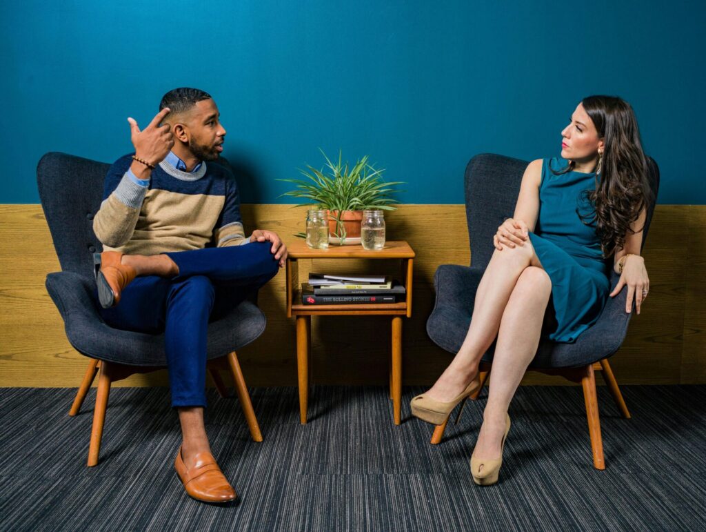 Elegant man and woman having a serious conversation, representing formal settings where signs you're a people pleaser might show up.