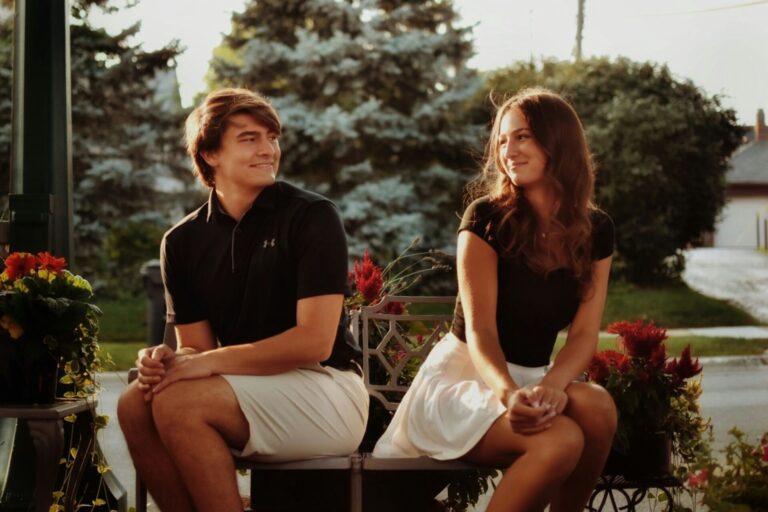 Teen boy and girl sitting side by side, smiling at each other with their legs turned outward — a moment that reflects the best relationship advice for teenagers about space and connection.