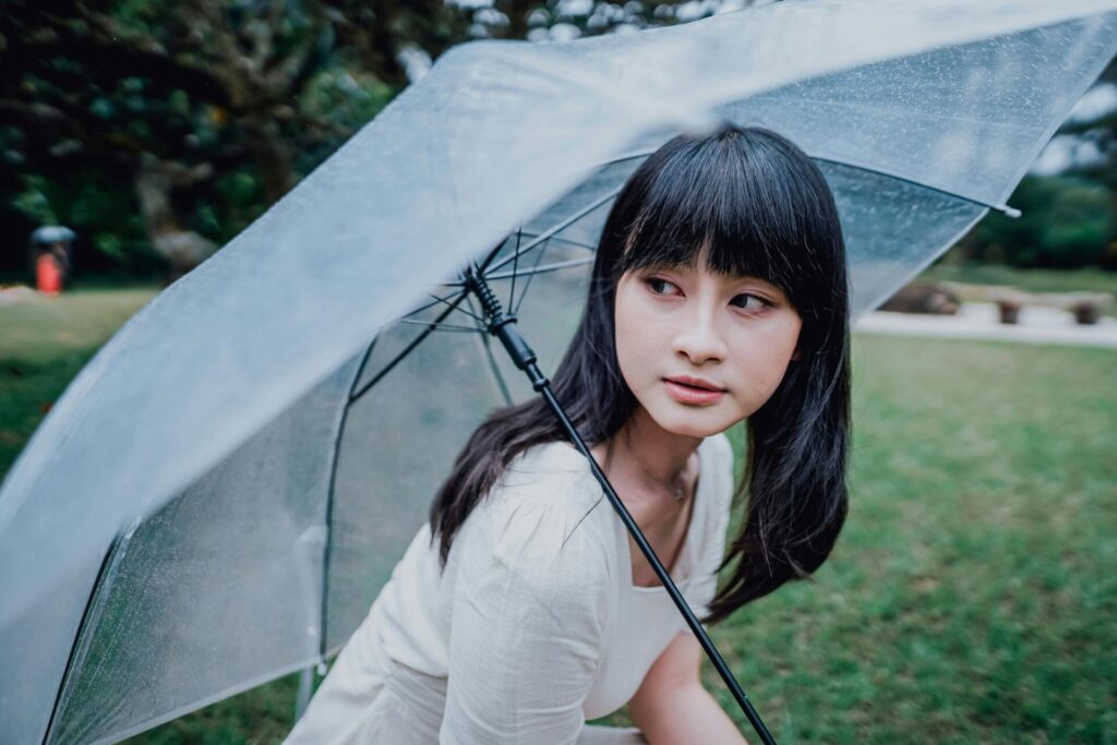 Dark-haired woman holding an umbrella outside, embracing rainy day activities for adults to stay entertained despite the weather.

