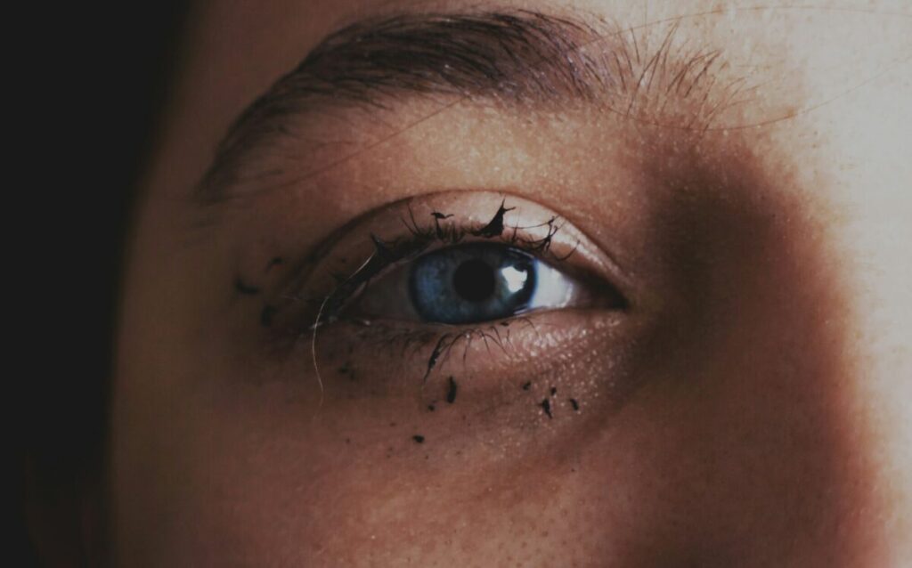 Close-up of a teary woman’s eye with smudged mascara, symbolizing reflection and questions to ask yourself after a breakup.