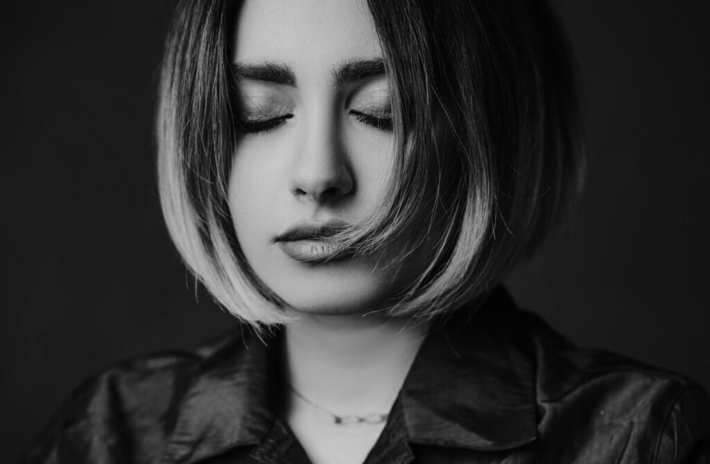 Sad woman sitting alone, reflecting on important questions to ask yourself after a breakup, black and white photo.