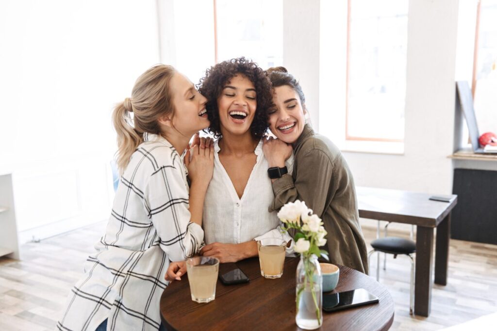 Three friends laughing together, sharing joy and positive energy