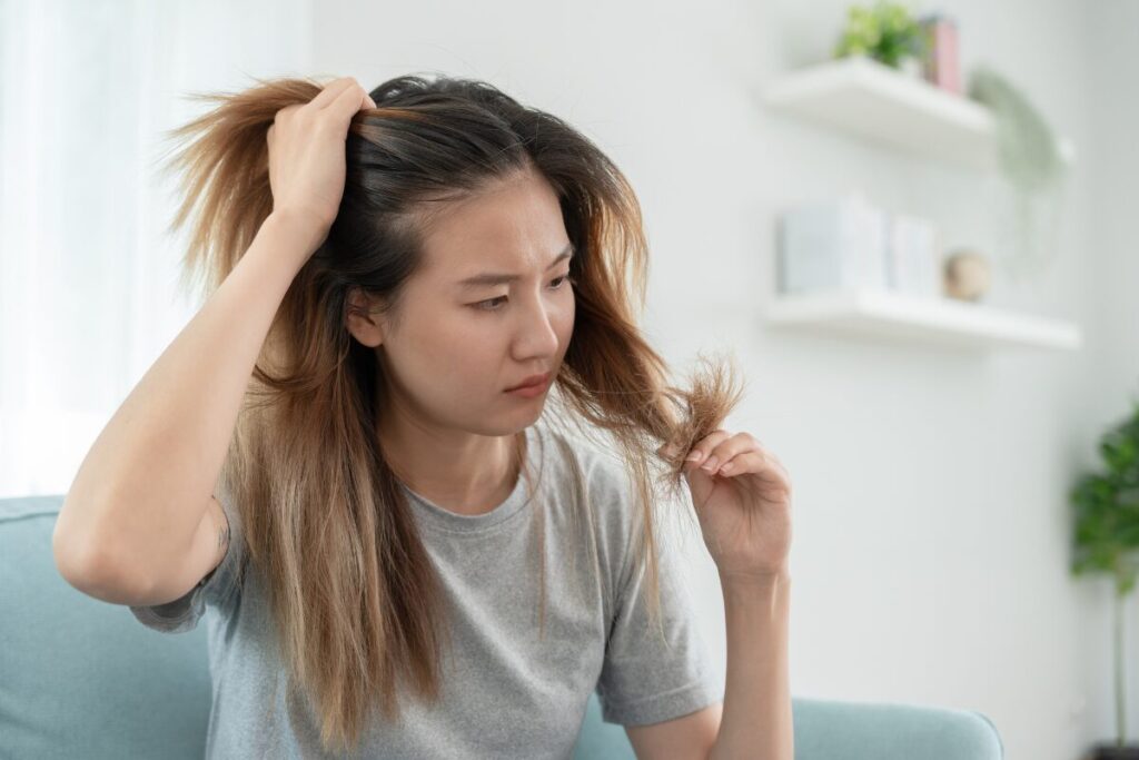 Woman checking her hair for thinning and dryness, a common sign of hormonal imbalance in women